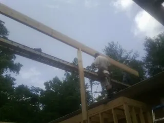 Carpenter setting a ridge beam over a new addition frame — Ice Dam Removal by Roofing Brothers in Grapeville