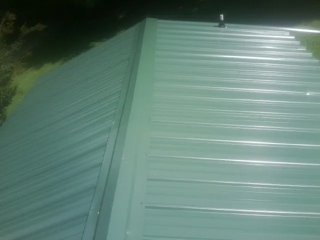 New green metal panels meeting at the ridge of a roof — Flat Roof Repair work by our crew in Grapeville