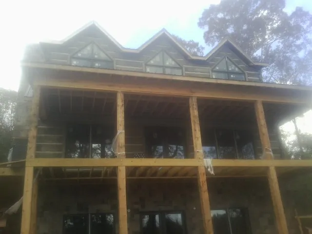 Dormers and porch framing on a large log home under construction — Roof Coating work by our crew in Grapeville