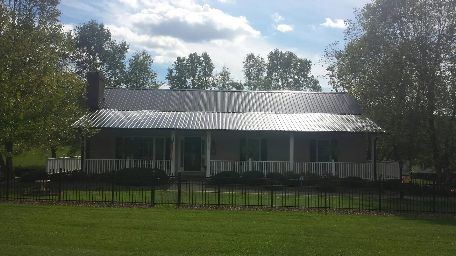 Gray metal roof on a brick ranch with a full width front porch — Gutter Guard Installation work by our crew in Grapeville