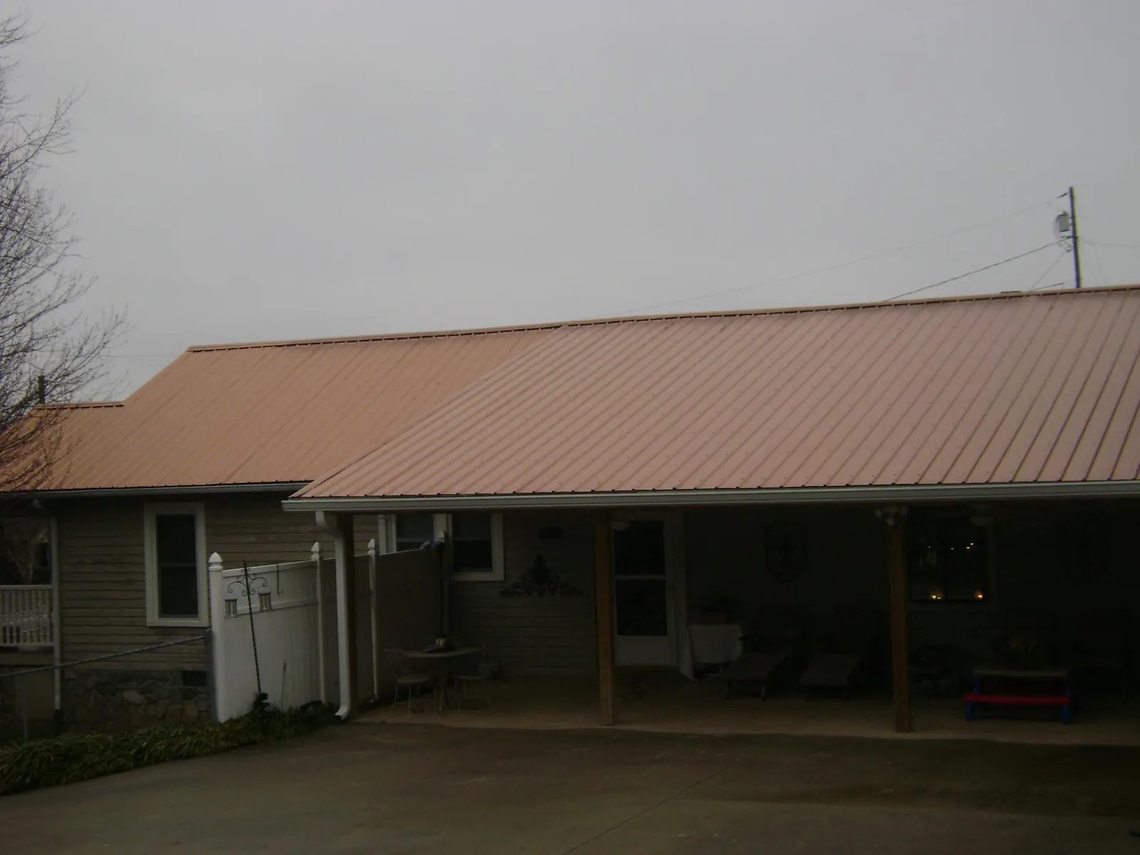 Copper toned metal roof over a wide covered patio in Grapeville
