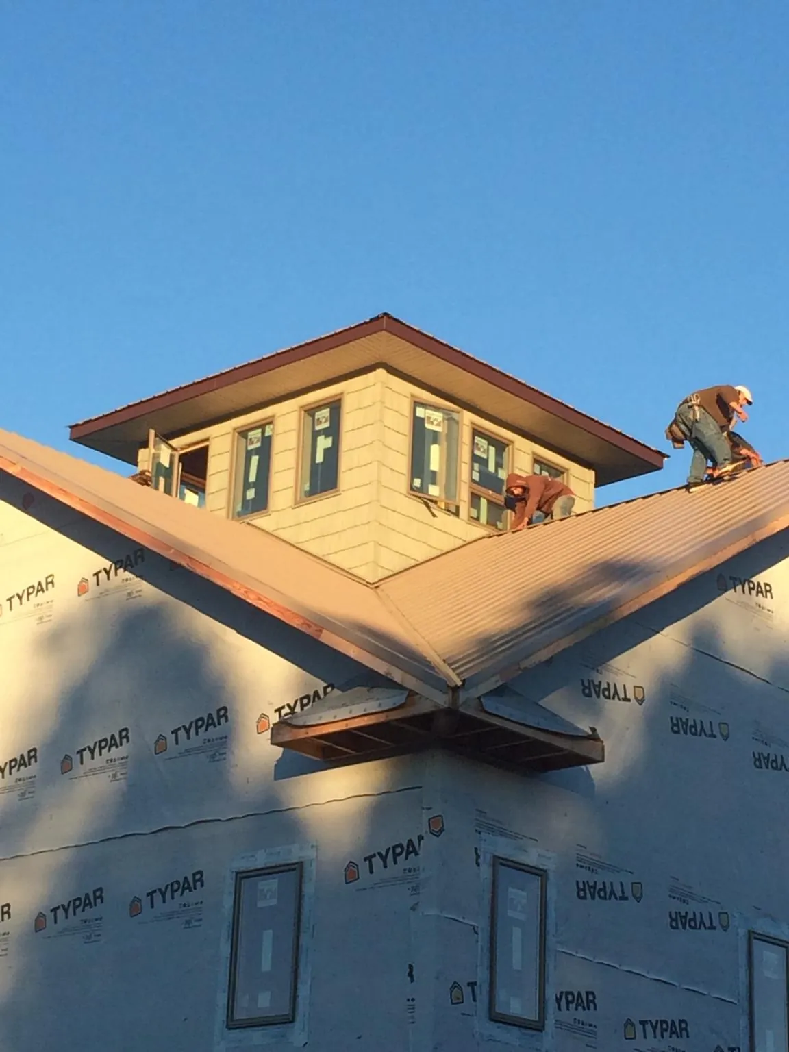 Roofers working around a rooftop cupola on a new metal roof at sunset — Roof Waterproofing in Grapeville by Roofing Brothers